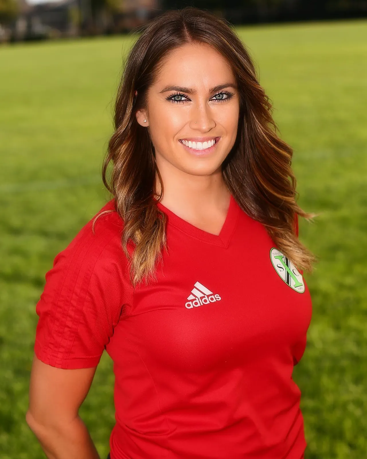 Cecy Martínez smiling on a soccer field in a red jersey